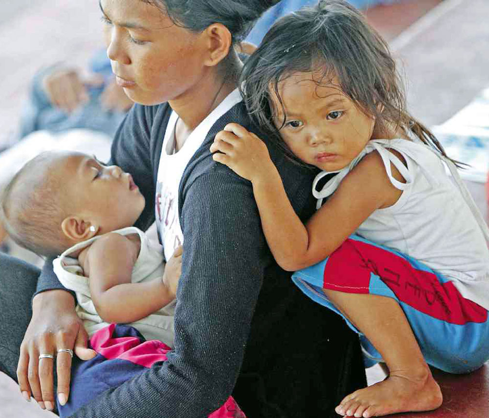 A woman and her two children wait for food to arrive at Joaquin F. Enriquez Memorial Sports Complex, where thousands of people have taken shelter from fighting between government forces and Moro rebels in Zamboanga City.  EDWIN BACASMAS