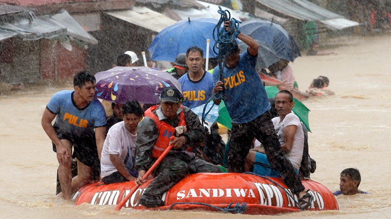 A man dives in the background as rescuers use a rubber dinghy to rescue trapped residents after continues heavy monsoon rains spawned by tropical storm Fung-Wong flooded Marikina city, east of Manila, Philippines and most parts of the metropolis Friday, Sept. 19, 2014. AP