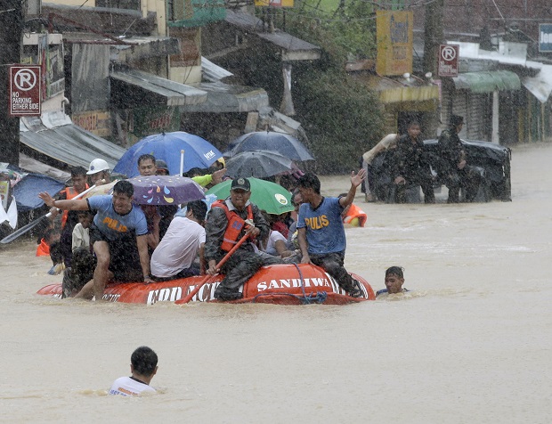 Rescuers use a rubber dinghy to rescue trapped residents after heavy monsoon rains spawned by tropical storm Fung-Wong flooded Marikina city, east of Manila, Philippines and most parts of  the metropolis Friday, Sept. 19, 2014. Heavy rains due to a storm and the seasonal monsoon caused widespread flooding Friday in the Philippine capital and nearby provinces, shutting down schools and government offices. Local authorities reported thousands were evacuated early Friday from severely inundated communities, some under rapid-flowing flood waters more than neck high.(AP Photo/Bullit Marquez)