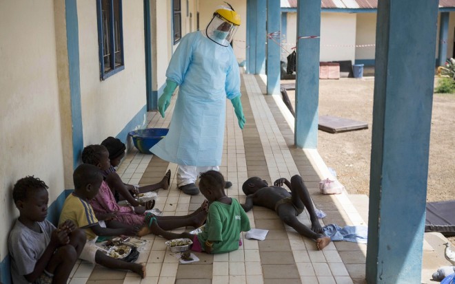 A health official dressed in protective gear examines children suffering from the Ebola virus at Makeni Arab Holding Centre in Makeni, Sierra Leone, October 4. AP 