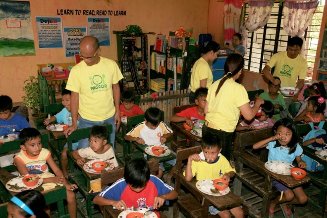 Employees of the Casino Filipino Laoag branch assist the beneficiaries of the PAGCOR Feeding Program during the project’s launch in Naguilian Elementary School in Nueva Era, Ilocos Norte. PAGCOR allocated more than P42 million for its nationwide feeding program for School Year 2014-2015.