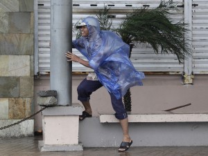 A man holds on to a pole as strong winds blow brought by Typhoon Hagupit in Legazpi, Albay province, eastern Philippines on Sunday, Dec. 7, 2014. Typhoon Hagupit slammed into the central Philippines' east coast late Saturday, knocking out power and toppling trees in a region where 650,000 people have fled to safety, still haunted by the massive death and destruction wrought by a monster storm last year. (AP Photo/Aaron Favila)