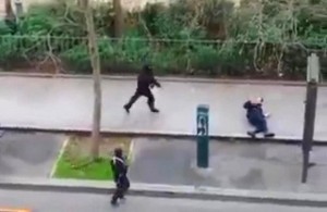 Masked gunman run towards a victim of their gun fire  outside the  French satirical newspaper Charlie Hebdo's office, in Paris, Wednesday, Jan. 7, 2015. Paris residents captured chilling video images of two masked gunmen shooting a police officer after an attack at a French satirical newspaper. In the video, the gunmen armed with assault rifles are seen running up to an injured police officer, who lies squirming on the ground. The police officer raises his hands up before one of the assailants shoots him in the head at a close range.  (AP Photo) NO SALES