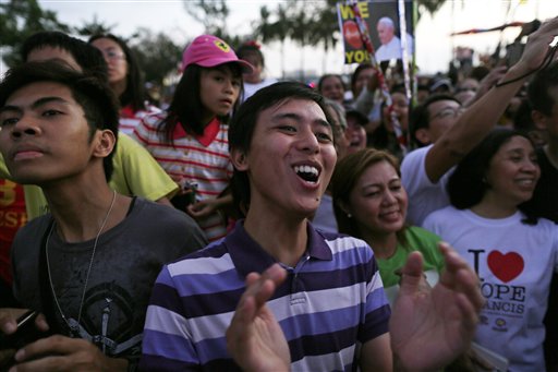 The faithful react as they watch a screen showing the arrival of Pope Francis in Manila, Philippines, Thursday, Jan. 15, 2015. Ecstatic crowds greeted Pope Francis as he arrived Thursday in the Philippines, Asia's most populous Catholic nation, for the first papal visit in 20 years. AP