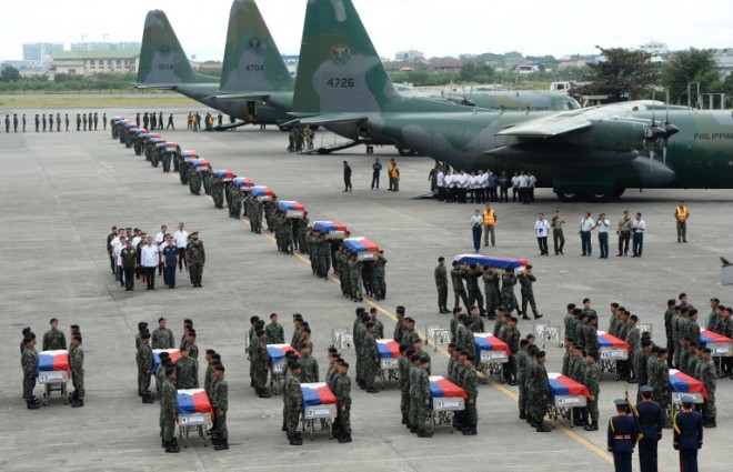 Philippine police commandos carry the flag-draped coffins of their fallen comrades from C-130 planes shortly after arriving at a military base in Manila on January 29, 2015.  A long, slow procession of Philippine-flag-draped coffins poured out of military transport planes in Manila on January 29 as the country mourned dozens of policemen killed in a botched anti-terror operation.     AFP PHOTO / TED ALJIBE