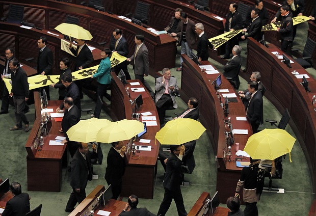 Pro-democracy legislators hold up yellow umbrellas and banners stating "I want real universal suffrage" and "Leung Chun-ying Step down" as they walk out of the Legislative Council during Hong Kong Chief Executive Leung Chun-ying's annual policy address in Hong Kong, Wednesday, Jan. 14, 2015. (AP Photo/Vincent Yu)