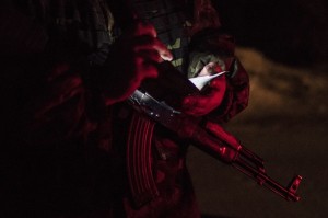 A Ukrainian serviceman checks a driver's documents as he guards a checkpoint in Severodonetsk, eastern Ukraine, Saturday, Feb. 21, 2015. Ukrainian military and separatist representatives exchanged dozens of prisoners under cover of darkness at a remote frontline location Saturday evening, kicking off a process intended to usher in peace to the conflict-ridden east. (AP Photo/Evgeniy Maloletka)