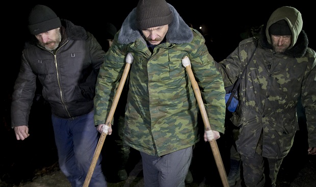 Ukrainian prisoners of war help an injured serviceman using crutches march before a prisoner exchange in separatist controlled territory, near Zholobok,  Ukraine, Saturday, Feb. 21, 2015. Ukrainian military and separatist representatives exchanged dozens of prisoners under cover of darkness at a remote frontline location Saturday evening. 139 Ukrainian troops and 52 rebels were exchanged, according to a separatist official overseeing the prisoner swap at a no mans land location near the village of Zholobok, some 20 kilometers (12 miles) west of Luhansk. (AP Photo/Vadim Ghirda)