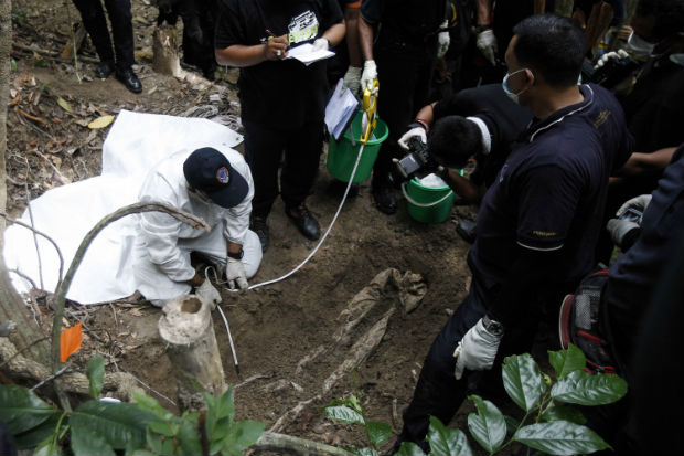 Malaysia clears grave sites as Thais seek stranded migrant boats.