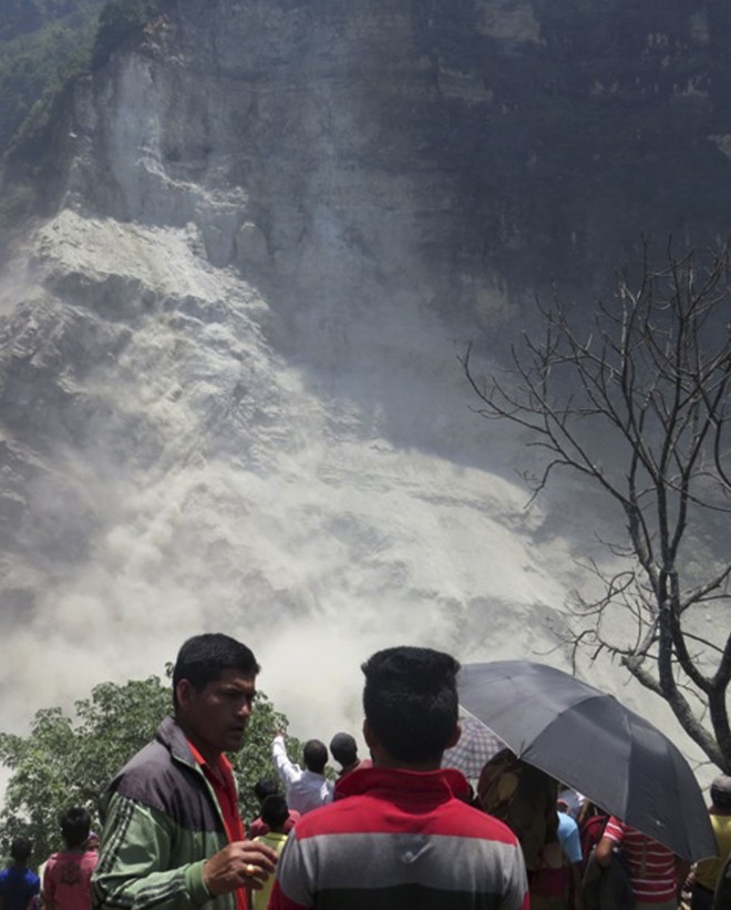 People gather at the site of a landslide north of Beni Bazaar, Nepal, Sunday, May 24, 2015. Thousands of people fled villages and towns along a mountain river in northwest Nepal on Sunday after it was blocked by a landslide that could burst and cause flash floods, officials said.  AP PHOTO/M.B. ASTHA 