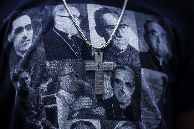 A man wears a cross and a T-shirt featuring portraits of Catholic Archbishop Oscar Romero during his beatification ceremony in San Salvador, El Salvador, Saturday, May 23, 2015. Romero was slain by an assassin's bullet 35 years ago and declared a martyr for his faith this year by Pope Francis. In life, Romero was loved by the poor, whom he defended passionately, and loathed by conservatives who considered him too close to left-leaning movements in the tumultuous years ahead of El Salvador's 1980-92 civil war. (AP Photo/Manu Brabo)