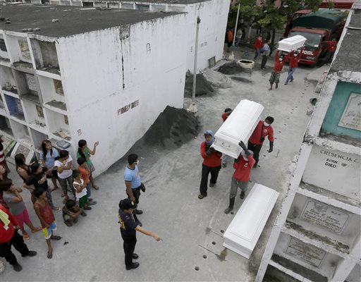 Workers carry coffins of fire victims for mass interment into apartment type-crypts Friday, May 15, 2015 at a public cemetery in Valenzuela city, a northern suburb of Manila, Philippines. AP