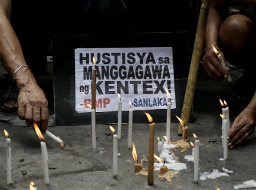 Protesters light candles in front of the burnt Kentex rubber slipper factory in Valenzuela city, a northern suburb of Manila, Philippines, Friday, May 15, 2015 to demand justice for the victims of a fire that gutted the factory Wednesday. AP