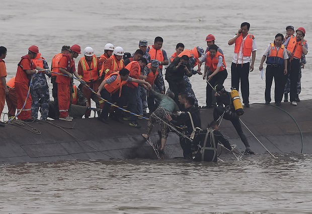In this photo released by China's Xinhua News Agency, rescuers save a survivor, center, from the overturned passenger ship in the Jianli section of the Yangtze River in central China's Hubei Province Tuesday, June 2, 2015. Rescuers pulled several survivors to safety after hearing cries for help Tuesday from inside a capsized cruise ship that went down overnight in a storm on China's Yangtze River, state broadcaster CCTV said. (Cheng Min/Xinhua via AP) NO SALES