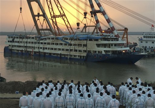 Paramilitary policemen in white overalls wait to recover bodies from the Eastern Star after it is righted and lifted by cranes in the Yangtze River in Jianli county in southern China's Hubei province Friday June 5, 2015. The smashed up white-and-blue Eastern Star emerged from gray waters of the Yangtze River on Friday as Chinese disaster teams raised the capsized ship with cranes to better search for hundreds still missing. AP PHOTO