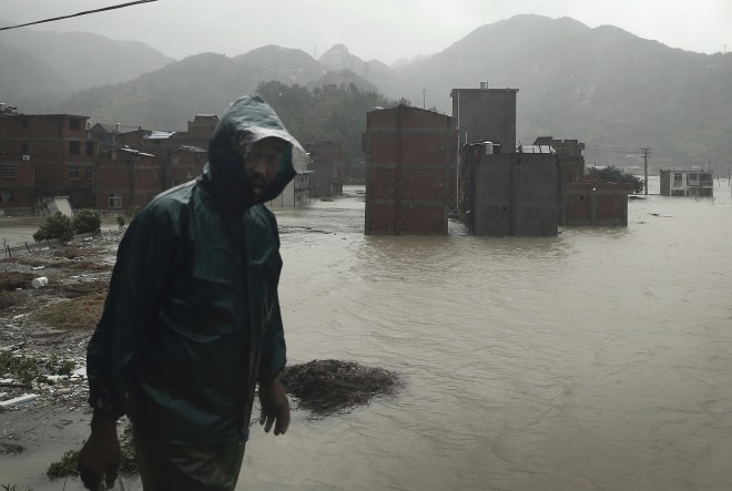 A man walks past a village submerged by water after it was hit by Typhoon Soudelor in Ningde, southeast China's Fujian province, Sunday, Aug. 9, 2015. Typhoon Soudelor that lashed Taiwan dumped heavy rain and winds on the Chinese mainland on Sunday, leaving dozens of people dead or missing, collapsing homes and trees and cutting power to more than a million homes. (Chinatopix via AP) CHINA OUT
