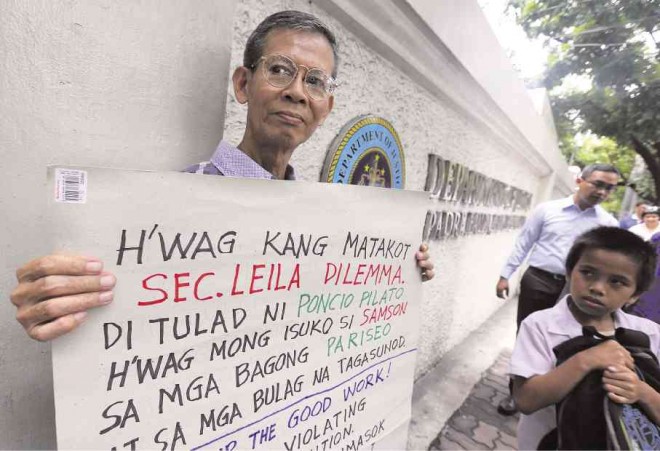 HE’S NOT ALONE  A boy curiously eyes Jose Kwe, 67, staging a solo rally at the Department of Justice (DOJ) on Padre Faura, Manila, on Tuesday. Kwe holds up a placard supporting Justice Secretary Leila “Dilemma,” urging her to stand her ground on the criminal charges filed by expelled Iglesia ni Cristo (INC) minister Isaias Samson against INC. The  sect massed in front of the DOJ and blocked De Lima’s car on Thursday, before proceeding to Edsa for a protest rally that blocked traffic for the next four days.  MARIANNE BERMUDEZ