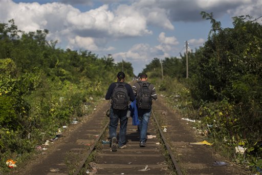 In this photo taken on Saturday, Sept. 12, 2015, Mohammed al-Haj, right, and his friend Dr. Mohanad Abdul-Qader walk on the railway tracks as they try to pass from the Serbian village of Horgos to Hungary. Mohammed, a 26-year-old from Aleppo, was one of more than 600,000 migrants and refugees who flowed into Europe so far this year. The Associated Press followed Mohammed on nearly every step of his 2,500-mile journey in September, starting from Killis, Turkey, where his family lived for a year after escaping Syria. (AP Photo/Santi Palacios)