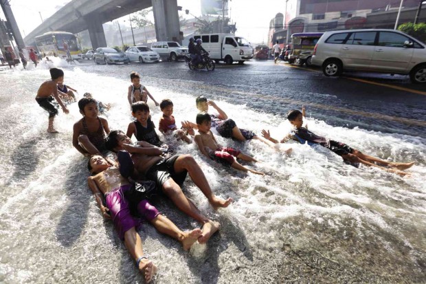 A Maynilad crew member watches helplessly (above) while children enjoy a roadside bath as a massive water leak inundates a major road in Sta. Mesa, Manila on Thursday. Niño Jesus Orbeta