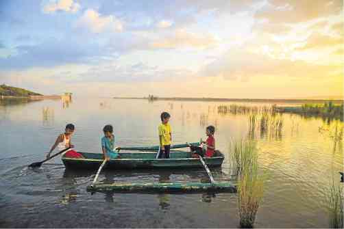 ROW YOUR BOAT   Children while their time away on a boat on a shallow portion of the reregulating pond below San Roque Dam’s spillways in San Manuel town in Pangasinan province. Water used to turn the turbines to produce electricity are released to this pond. The National Irrigation Administration, in turn, regulates the release of irrigation water to rice fields in eastern and central Pangasinan towns.  ROGER TINGLE / Contributor