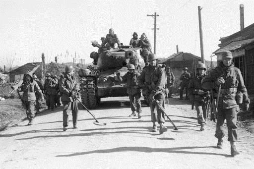  In this Nov. 25, 1950, file photo, men of the U.S. 24th division sweep the road ahead of a tank as they advance into Chongju, North Korea, during the Korean War. "Until They Are Home" is one of the most sacred vows of the U.S. military, yet there are 5,300 American GIs missing in North Korea from the Korean War whose remains are potentially recoverable. It has been more than a decade since any U.S. search teams have tried, and with construction projects across the country moving forward, many could already be lost forever. (AP Photo/Max Desfor, File )