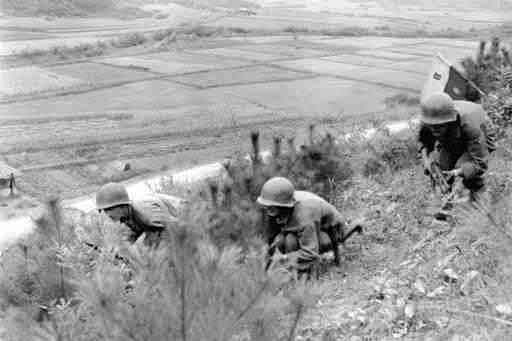 In this Oct. 15, 1950, file photo, Eighth U.S. Cavalry Regiment soldiers advance through low brush in North Korea during the Korean War. "Until They Are Home" is one of the most sacred vows of the U.S. military, yet there are 5,300 American GIs missing in North Korea from the Korean War whose remains are potentially recoverable. It has been more than a decade since any U.S. search teams have tried, and with construction projects across the country moving forward, many could already be lost forever. (AP Photo/Max Desfor, File )