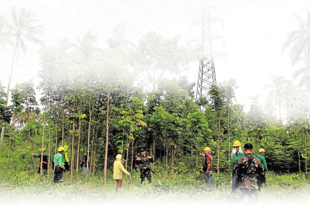 Power transmission towers in Mindanao are constantly under threat from bombers.  In this 2016 photo, workers from the National Grid Corporation of the Philippines and soldiers guard one tower in Lanao del Norte.  (Photo by Richel Umel, INQUIRER MINDANAO