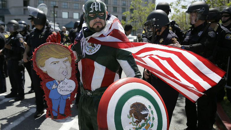 Erik Lopez, dressed as "Captain Mexico", stands in front of police officers while protesting Republican presidential candidate Donald Trump outside of the Hyatt Regency hotel during the California Republican Party 2016 Convention in Burlingame, Calif., Friday, April 29, 2016. (AP Photo/Eric Risberg)