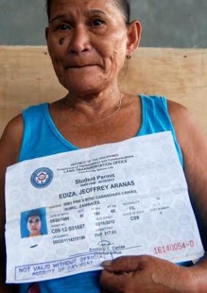 Violeta Ediza, mother of missing 29-year-old fisherman Joeffrey Ediza from Subic, Zambales, holds an enlarged copy of her son's identification card. She appealed to maritime and Navy authorities to send search and rescue teams to Occidental Mindoro, hoping that he could still be found alive. (Photo by Allan Macatuno, Inquirer Central Luzon)