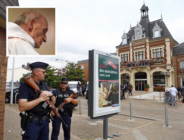 French police officers stand guard in front of the Saint-Etienne-du-Rouvray's city hall, Normandy, France, after an attack on a church that left a priest dead, Tuesday, July 26, 2016. Two attackers invaded a church Tuesday during morning Mass near the Normandy city of Rouen, killing an 84-year-old priest by slitting his throat and taking hostages before being shot and killed by police, French officials said. (AP Photo/Francois Mori)