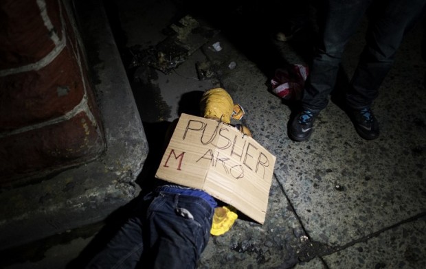 EDITORS NOTE: Graphic content / In this picture taken on July 8, 2016, police officers investigate the dead body of an alleged drug dealer, his face covered with packing tape and a placard reading "I'm a pusher", on a street in Manila.  Philippine President Rodrigo Duterte on July 1 urged communist rebels to start killing drug traffickers, adding another layer to a controversial war on crime in which he has warned thousands will die. / AFP PHOTO / NOEL CELIS / GRAPHIC CONTENT