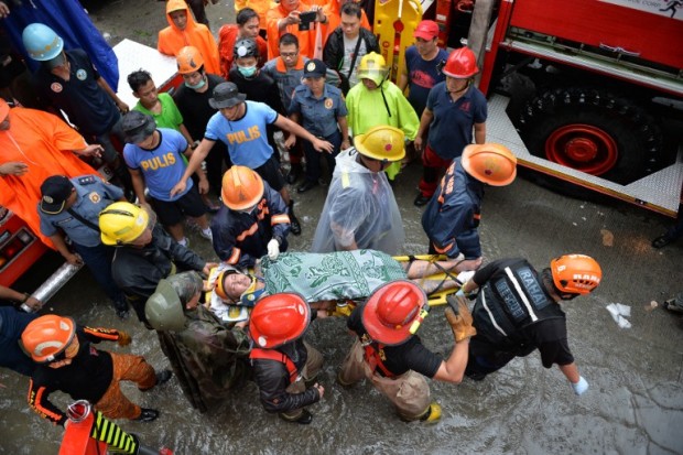 Rescue workers carry a survivor on a stretcher, after he was extracted from a collapsed wall in an informal settler house, just beside the city jail building in Manila on August 13, 2016.   Two residents were killed and nine injured when a wall collapsed after heavy rains overnight, according to local authorities. / AFP PHOTO / TED ALJIBE
