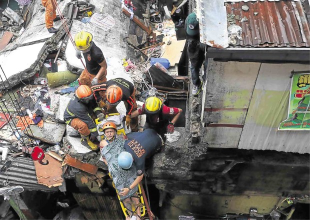 SHANTYTOWN TRAGEDY. Rescuers pull out a survivor from the rubble after a wall fell on a cluster of shanties in Sta. Cruz, Manila, on Saturday morning. Four more residents were injured while two teenage girls were crushed to death. Around 25 neighboring families were ordered to evacuate. MARIANNE BERMUDEZ