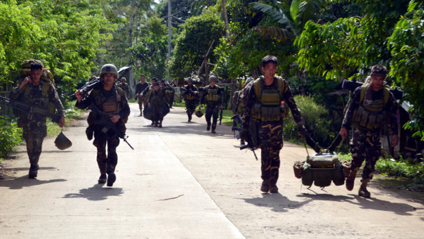 Philippine soldiers walk along a highway as they return to camp after an armed encouter with members of militant group Abu Sayyaf at the village of Bongkaong, Patikul town, Sulu province on the southern island of Mindanao on August 26, 2016. Philippine security officials killed six members of militant group Abu Sayyaf on August 26 including one involved in the kidnapping of two Canadians who were beheaded in the troubled south, the military said. / AFP PHOTO / STRINGER 