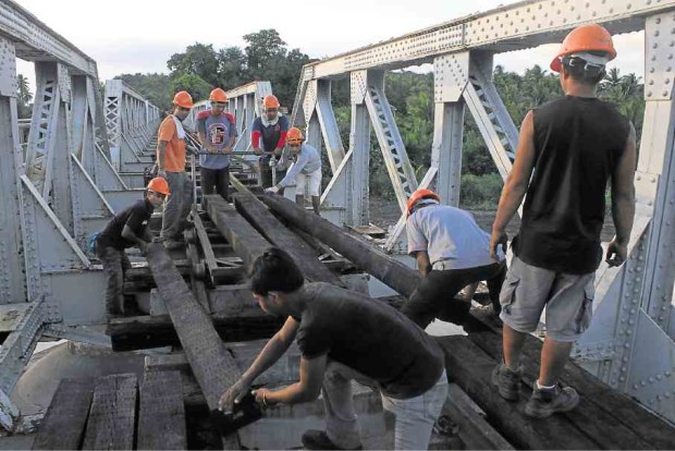 Laborerswork overtime to repair the rail bridge in Ragay, Camarines Sur, in preparation for the resumption of the Bicol Express.