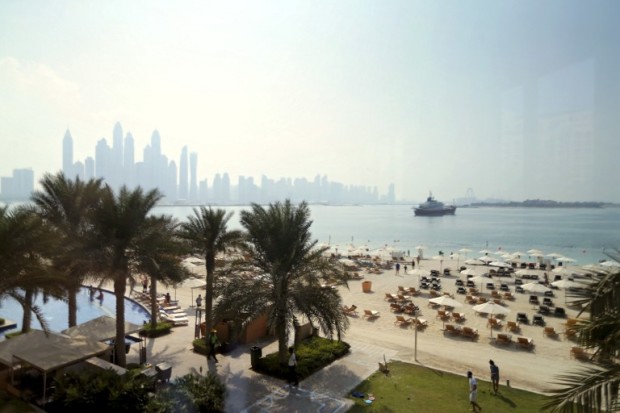 A picture taken from behind a window, shows the Palm Beach hotel, with the Dubai skyline seen in the background, on November 4, 2016. / AFP PHOTO / KARIM SAHIB