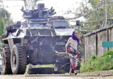 LIVING WITH CONFLICT A resident of Butig in Lanao del Sur province passes by a military vehicle as soldiers pursue members of the Maute terror group and Abu Sayyaf in the town. —JEOFFREY MAITEM