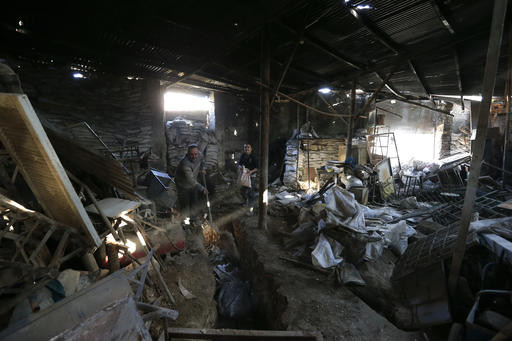 In this Jan. 20, 2017 photo, Syrians fill a tunnel used by rebel fighters with sand, inside their family's shop in the once rebel-held Bab Antakya street, in eastern Aleppo, Syria. Aleppo, Syria’s largest city, was widely brought to ruin by years of war, and now with Russia and Turkey leading peace efforts, international officials say it is time to start talking about rebuilding Aleppo and other cities. But there are few answers on how to do it, with the world reluctant to donate the billions needed and a political settlement in the war still uncertain and far off.  (AP Photo/Hassan Ammar)