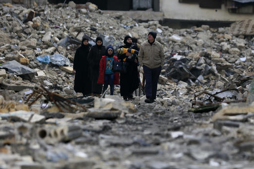 In this Jan. 20, 2017 photo, residents walk through the rubble of the once rebel-held Ansari neighborhood of eastern Aleppo, Syria. Aleppo, Syria’s largest city, was widely brought to ruin by years of war, and now with Russia and Turkey leading peace efforts, international officials say it is time to start talking about rebuilding Aleppo and other cities. But there are few answers on how to do it, with the world reluctant to donate the billions needed and a political settlement in the war still uncertain and far off. (AP Photo/Hassan Ammar)