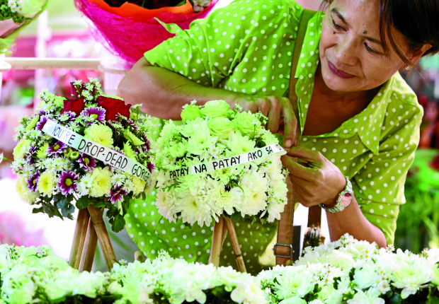 UNDYING LOVE Florist Jo Calderon gets creative in her shop in Taguig City by pinning humorous love messages on her miniature wreaths for sale on Valentine’s Day. —MARIANNE BERMUDEZ