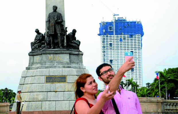 ‘PHOTOBOMB’  A tourist takes a selfie in front of the Rizal Monument at Luneta Park in Manila, with Torre de Manila, dubbed “national photobomb,” then undergoing construction in the background. —ARNOLD ALMACEN
