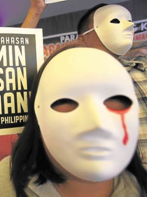 Members of human rights groups wear masks with red tears painted on them to protest street killings. —NIÑO JESUS ORBETA