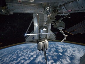 This image provided by NASA shows a view of the space shuttle Atlantis while still docked with the International Space Station taken by crew member Mike Fossum aboard the station Monday July 18, 2011. The robotic arm on the shuttle appears to be saluting "good-bye" to the station. Earth's airglow is seen as a thin line above Earth's horizon. The Raffaello multi-purpose logistics module, full of items to be returned to Earth, is seen in the aft cargo bay. AP