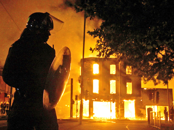 ANARCHY IN THE UK. A building burns as a riot police officer watches in Croydon, south London, Monday, Aug. 8, 2011. Violence and looting spread across some of London's most impoverished neighborhoods on Monday, with youths setting fire to shops and vehicles, during a third day of rioting in the city that will host next summer's Olympic Games. AP Photo/PA, Dominic Lipinski