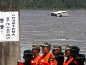 In this photo taken Wednesday Sept. 21, 2011, paramilitary policemen guard on a bridge as a building is submerged by diverted floodwaters at Dujiatai area in Xiantao city, in central China's Hubei province. The floods have swelled rivers in nine provinces, including Henan, Shaanxi and Sichuan, forcing nearly 1 million people to flee their homes, the Ministry of Civil Affairs said on its website late Wednesday. AP photo