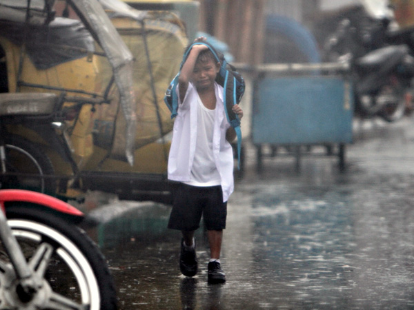An elementary school pupil  drenched in the rain cries while walking home along Batasan Road in Quezon City Tuesday morning as local government officails suspend classes due to heavy rains caused by a low pressure area. INQUIRER FILE PHOTO