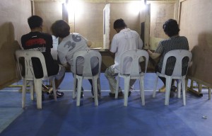 A Filipino woman leans over to consult her husband as they vote at a basketball gym used as a voting center during mid-term elections in Manila, Philippines on Monday May 13, 2013. The country is electing local officials from senators to congressmen and down to municipal mayors during today's mid-term elections. (AP Photo/Aaron Favila)