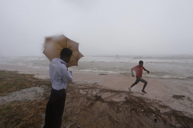 A Sri Lankan man tries to hold his umbrella against the strong wind as a boy runs in Dehiwala on the outskirts of Colombo, Sri Lanka, Saturday, June 8, 2013. Naval boats and helicopters scoured seas off Sri Lanka on Monday for dozens of missing fishermen, as the death toll from heavy monsoon rains and strong winds rose to 40, an official said.  AP PHOTO/ERANGA JAYAWARDENA