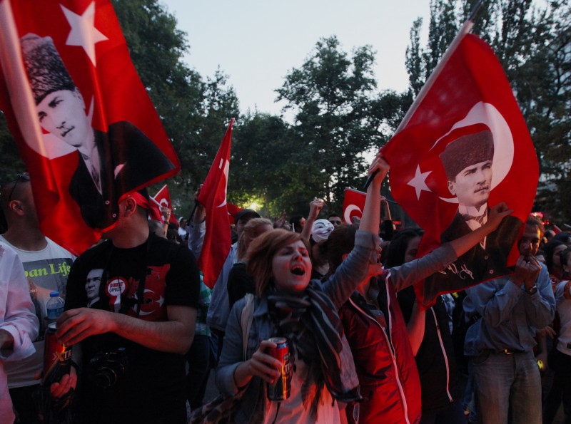 Turkish protesters wave national flags with portraits of Turkey's founder Kemal Ataturk as they take part in an anti-government rally in Ankara, Sunday, June 9, 2013. In a series of increasingly belligerent speeches to cheering supporters Sunday, Turkey's prime minister Recep Tayyip Erdogan launched a verbal attack on the tens of thousands of anti-government protesters who flooded the streets for a 10th day, accusing them of creating an environment of terror.(AP Photo/Burhan Ozbilici)