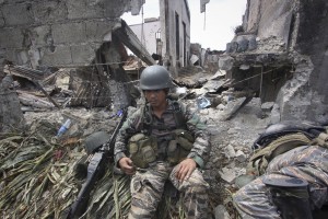 A Government trooper rests amidst the ruins at the site of a three-week intense fighting between Government forces and Muslim rebels who have taken nearly 200 people hostages and used them as human shields, Saturday Sept. 28, 2013 in Zamboanga city, southern Philippines. AP FILE PHOTO